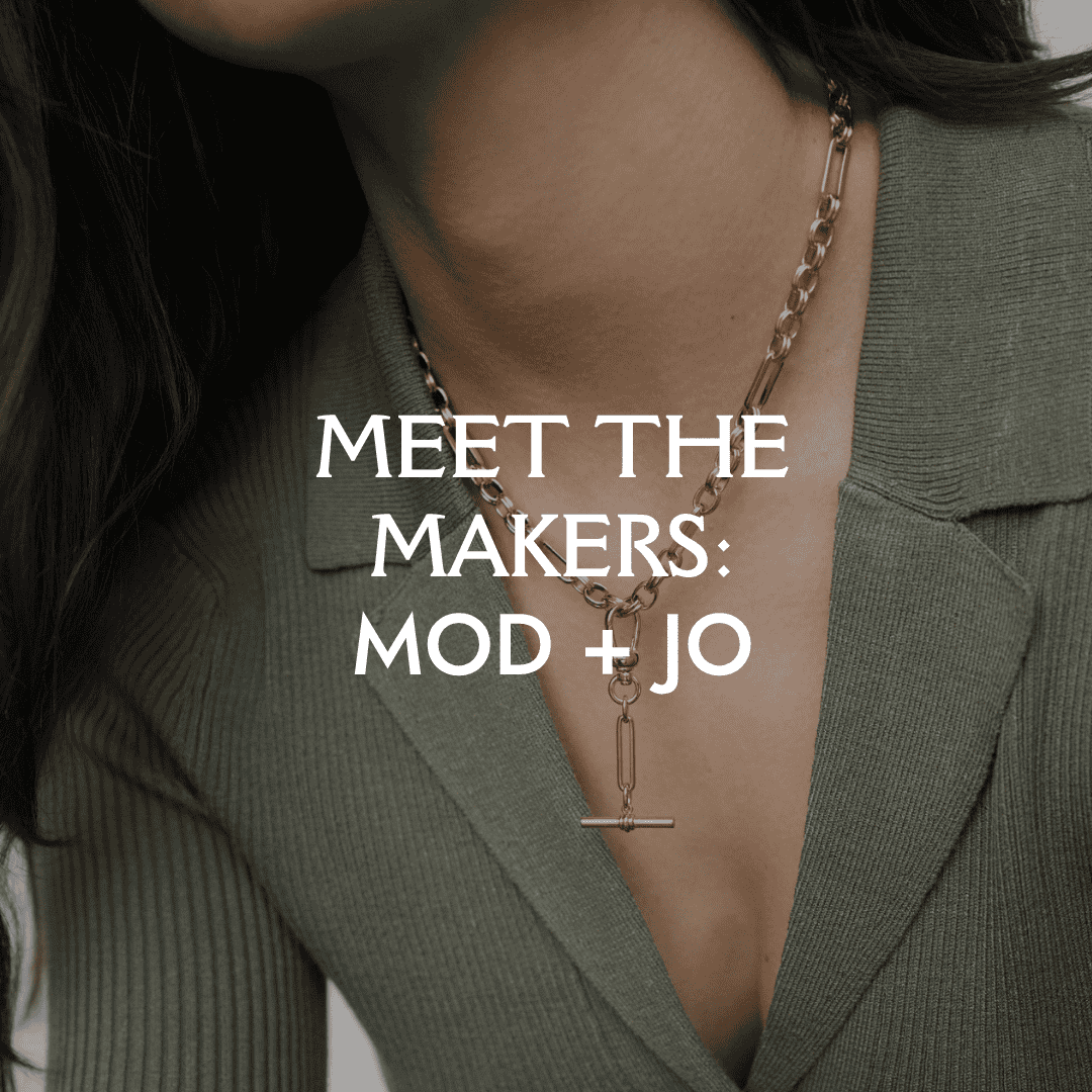 Close-up of Mod + Jo gold chain necklace with toggle clasp worn over deep V-neck green top, header image for ‘Meet the Makers’ jewelry feature by Brave Daughters.