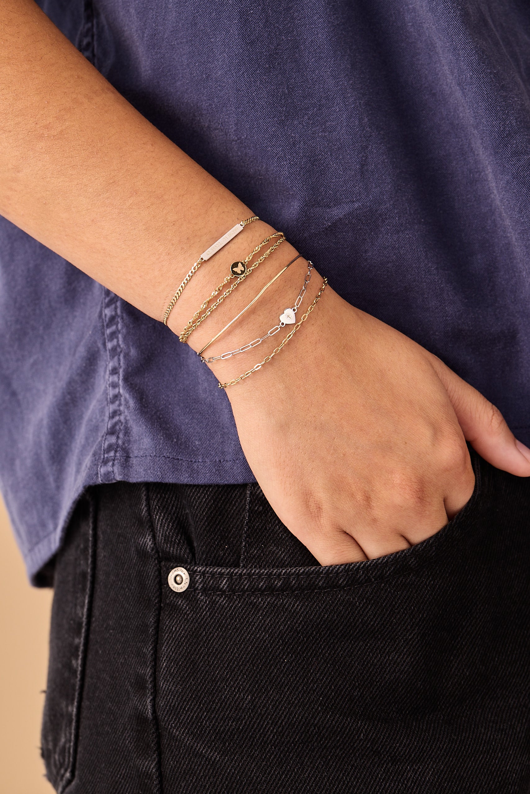 Custom permanent jewelry stack from Brave Daughters with gold and white gold welded chains, personalized bar, and heart charm — handcrafted fine jewelry designed for layering.