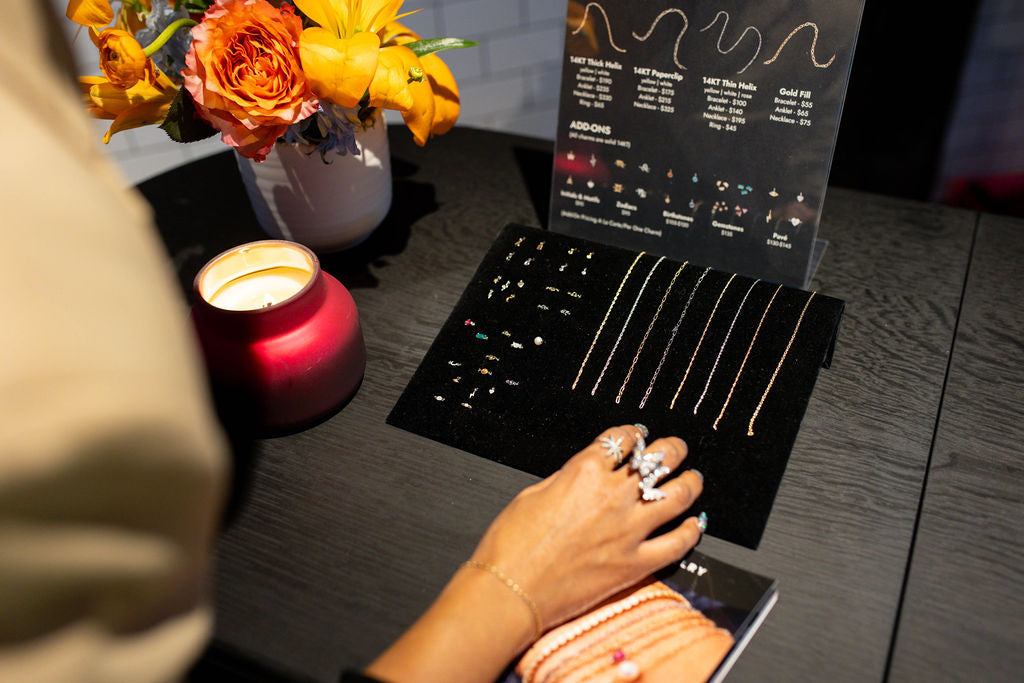 Permanent jewelry welding station by Brave Daughters with neon lightning bolt, professional lamp, and gold chain display. Ideal for on-site events, pop-ups, and personalized jewelry experiences.