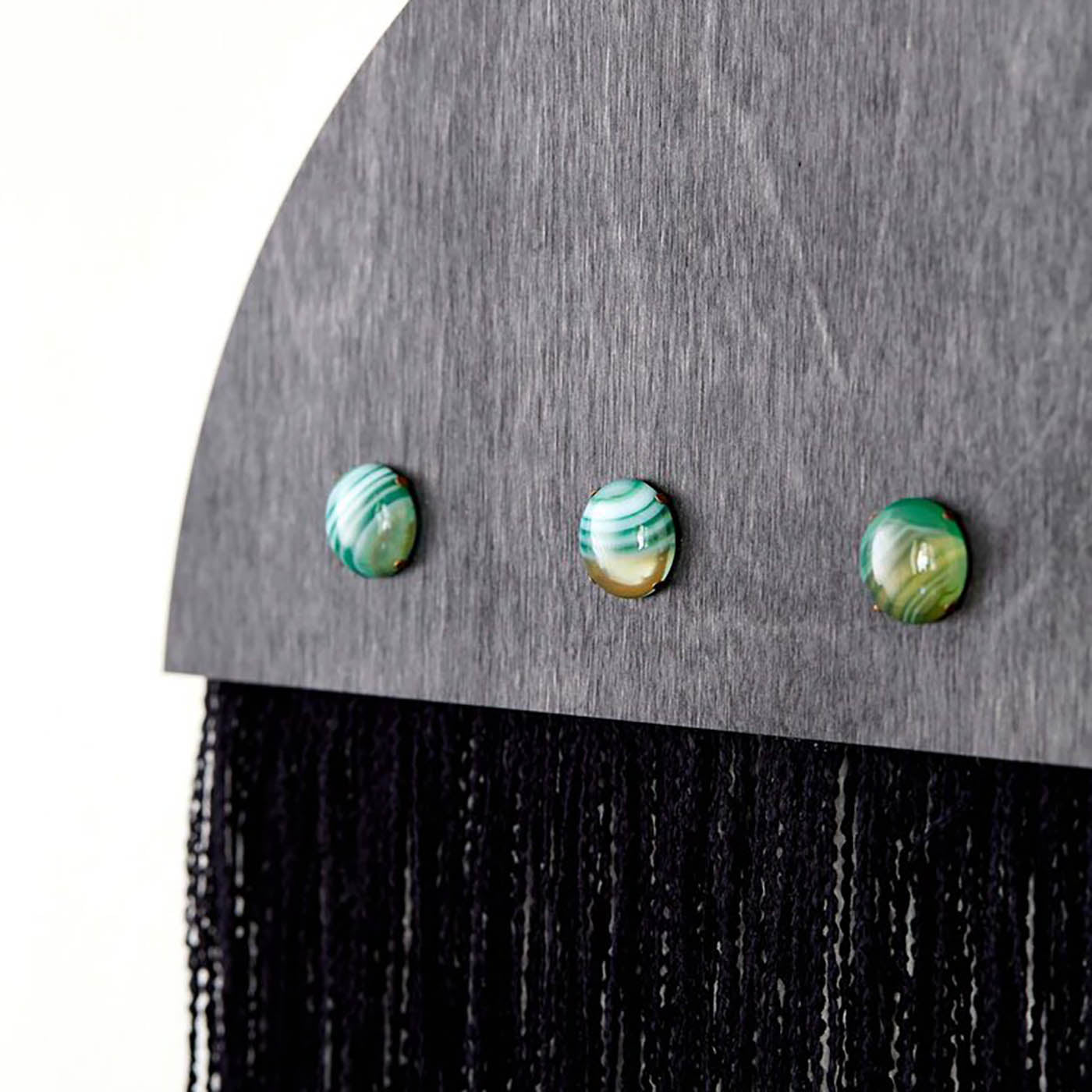 Half-moon shaped Ascension Wall Hanging featuring ebony stained wood, three agate cabochons, and black fringe detailing, highlighting sustainable craftsmanship.