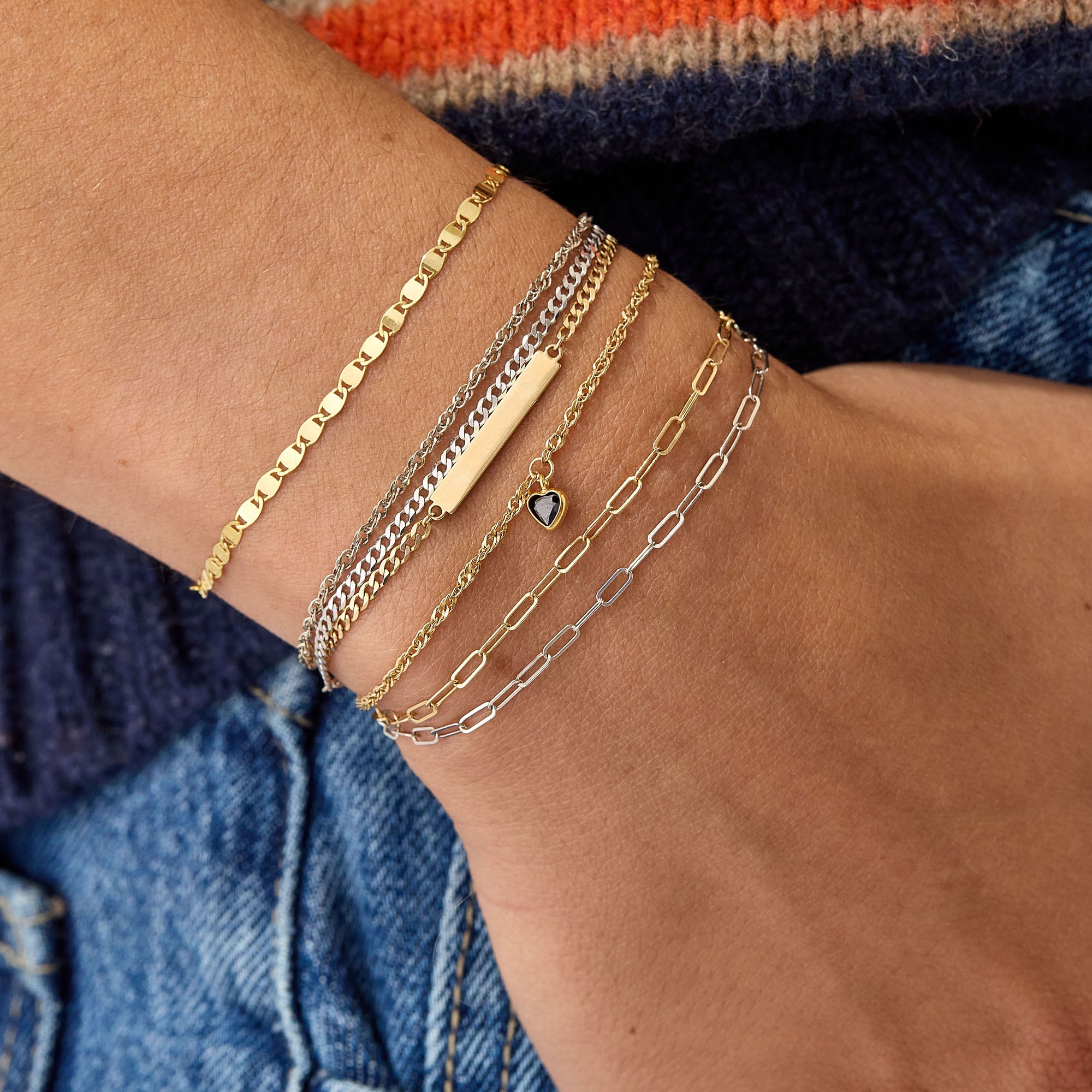 Stack of permanent bracelets featuring solid 14k gold chains and custom charms, showcasing luxury forever jewelry style.