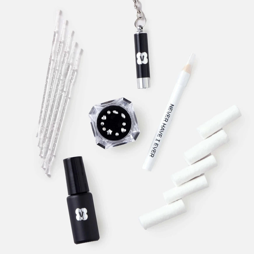 Set of makeup tools including brushes, adhesive, and a UV light keychain on a white background