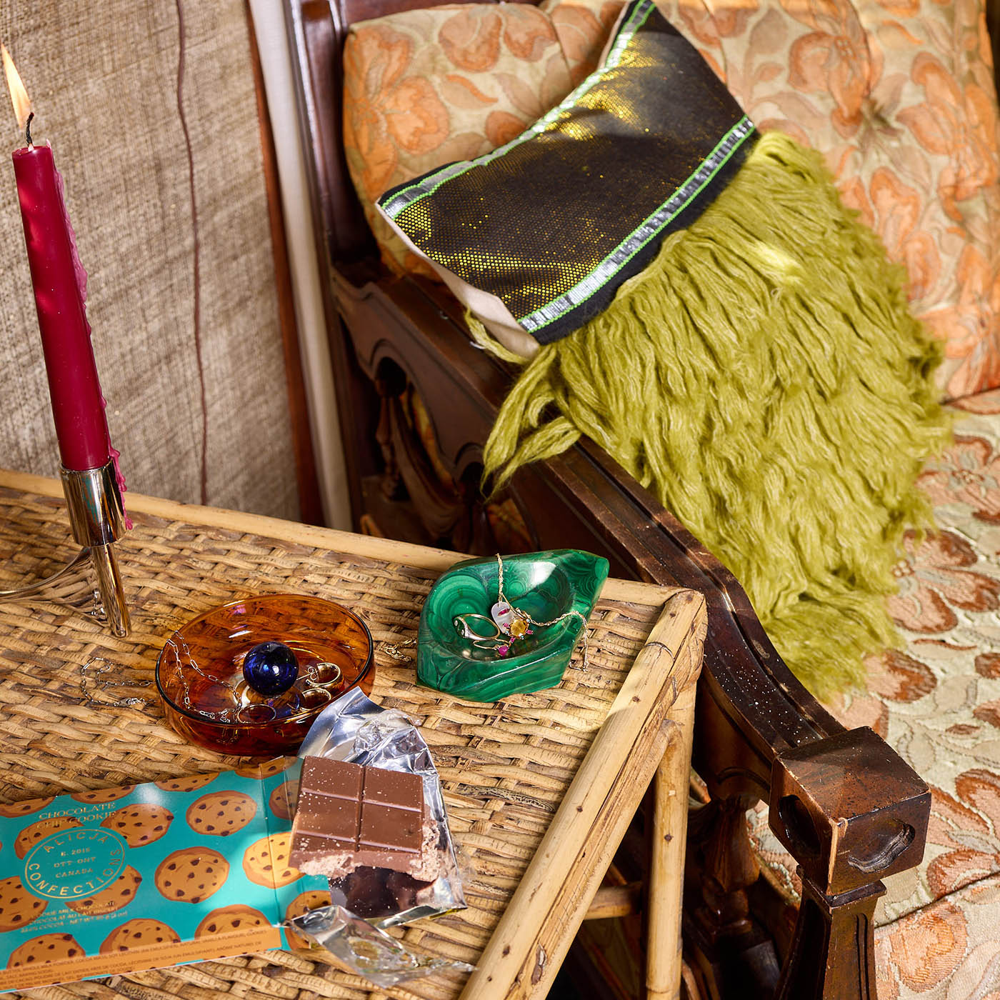 Small bubble glass catch-all dish in amber and cobalt with decorative elements, surrounded by jewelry, chocolate, and a candle on a woven table, showcasing a cozy home aesthetic.