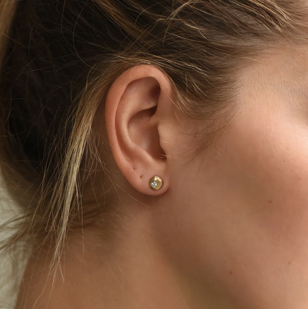 Sapphire chunky huggie hoop earring showcased on model's ear, highlighting minimalist design and brass material.