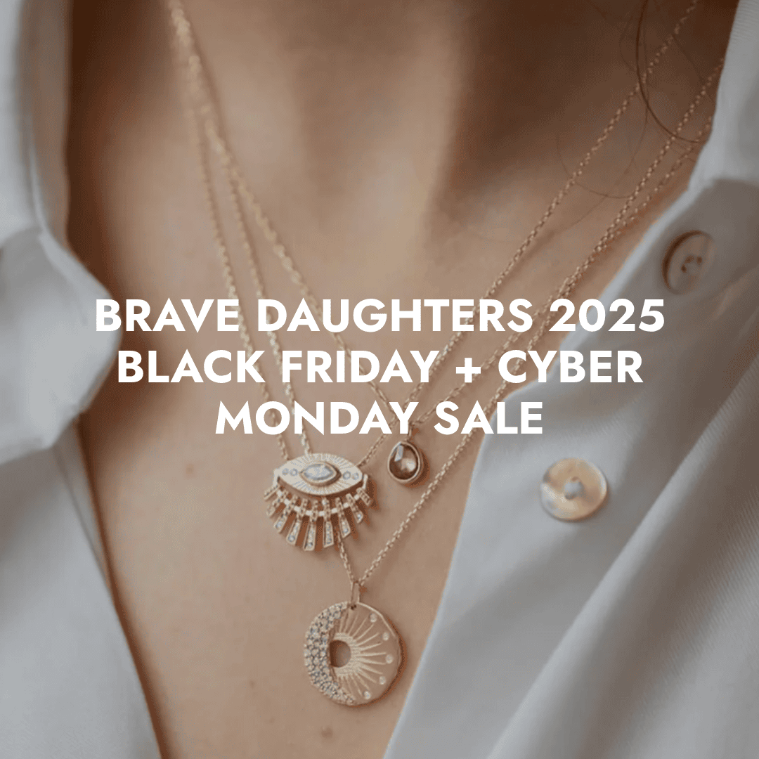 Close-up of layered gold necklaces with gemstone and sunburst pendants, with the text “Brave Daughters 2025 Black Friday + Cyber Monday Sale” overlaid on the image.