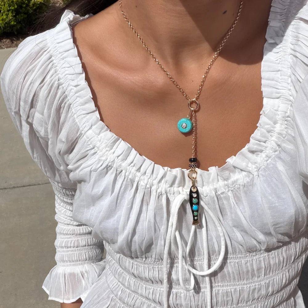 Close-up of a person wearing a white dress with a detailed necklace.