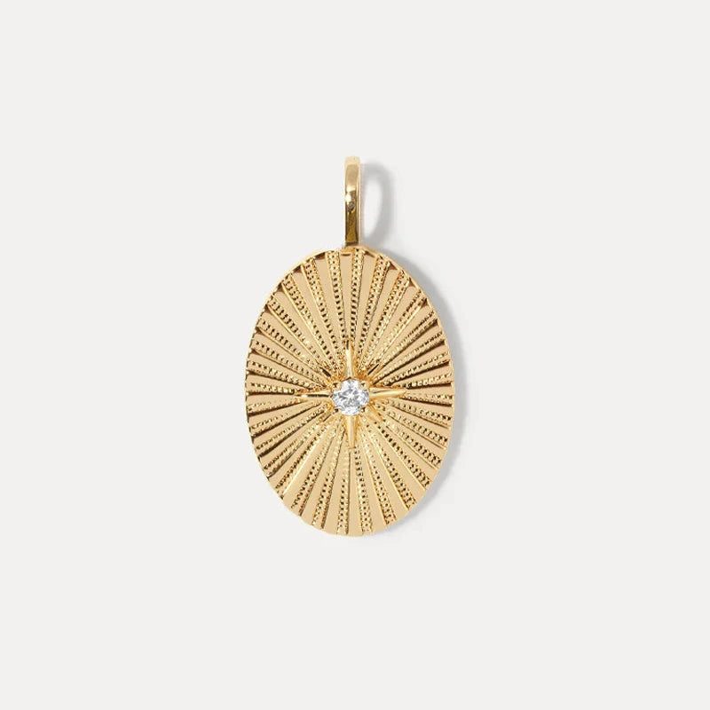 a gold oval charm with a star motif and stone accent on a white background
