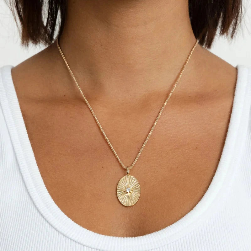 Gold necklace with a pendant worn by a person against a white background