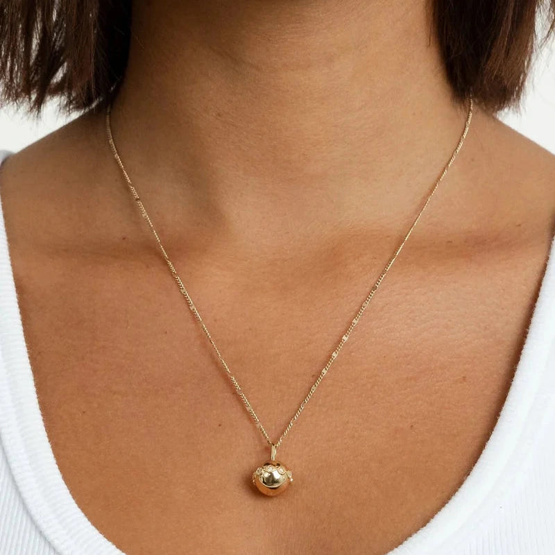 Gold necklace with a pendant on a person wearing a white top