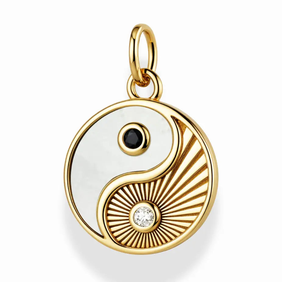 Gold yin yang pendant with black and clear gemstones on a white background
