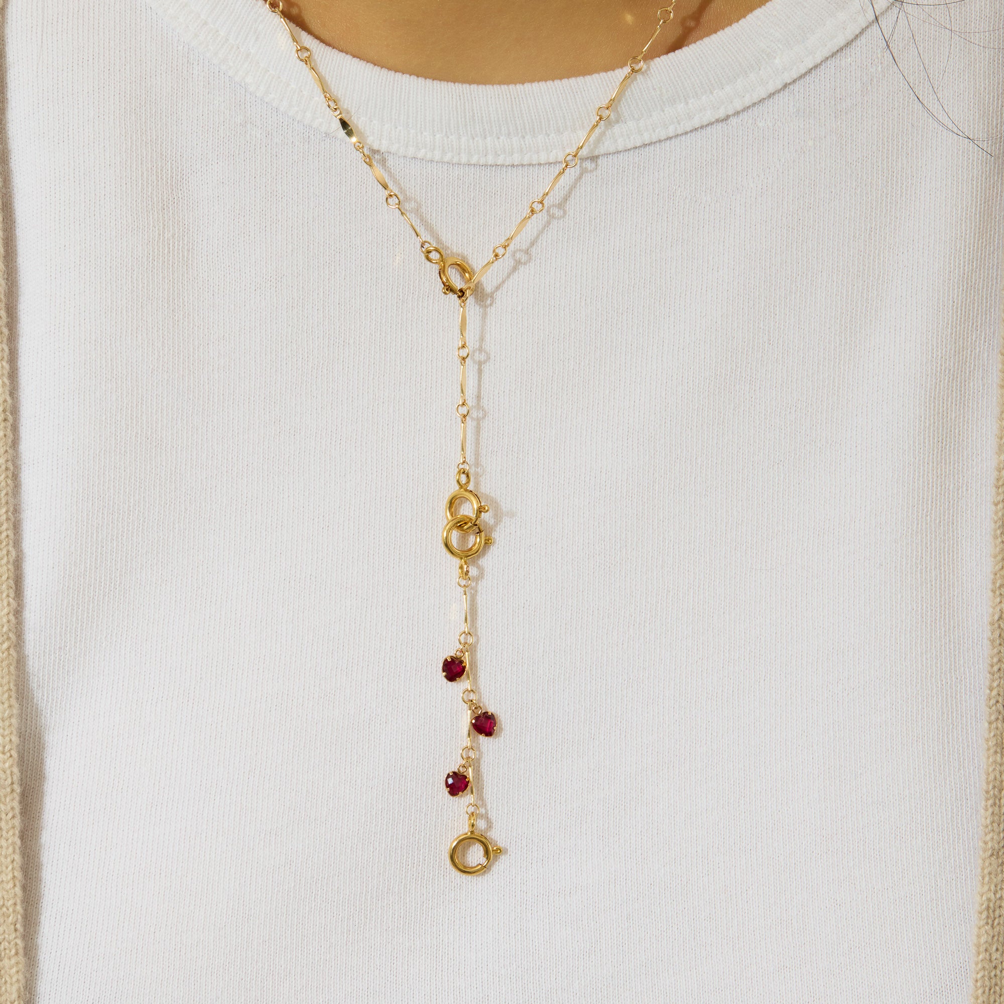Gold necklace with red hearts on a white background