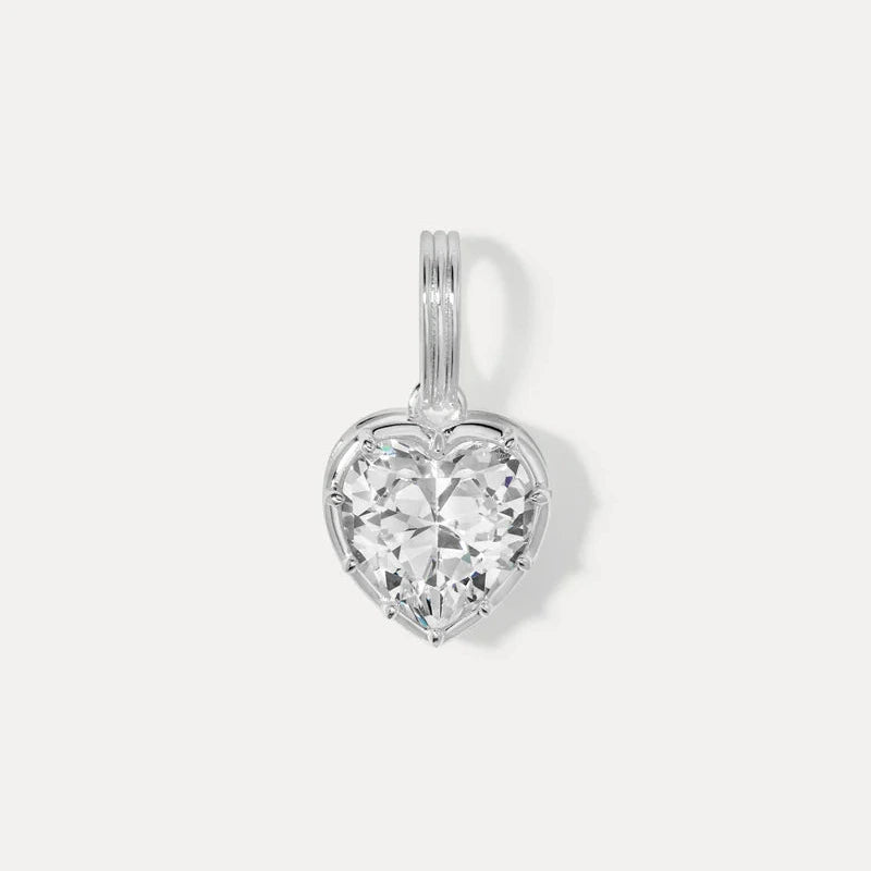 a silver heart charm with a bezel set faceted white cz on a white background