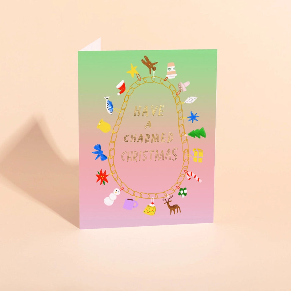 a greeting card with a purple to green gradient background and a text reading have a charmed christmas, surrounded by an illustrated charm bracelet