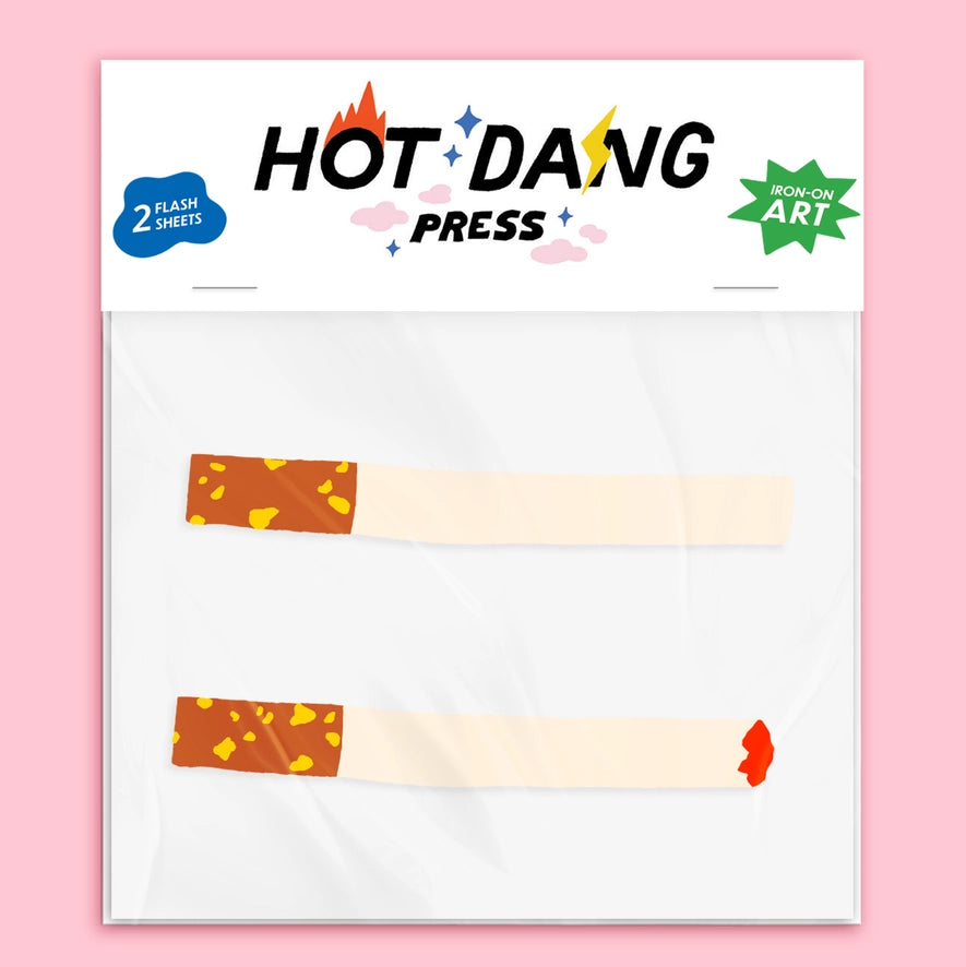 A packaged novelty item labeled HOT DANG PRESS, showing two flat cigarette-shaped flash sheets on a white backing card against a pink background.