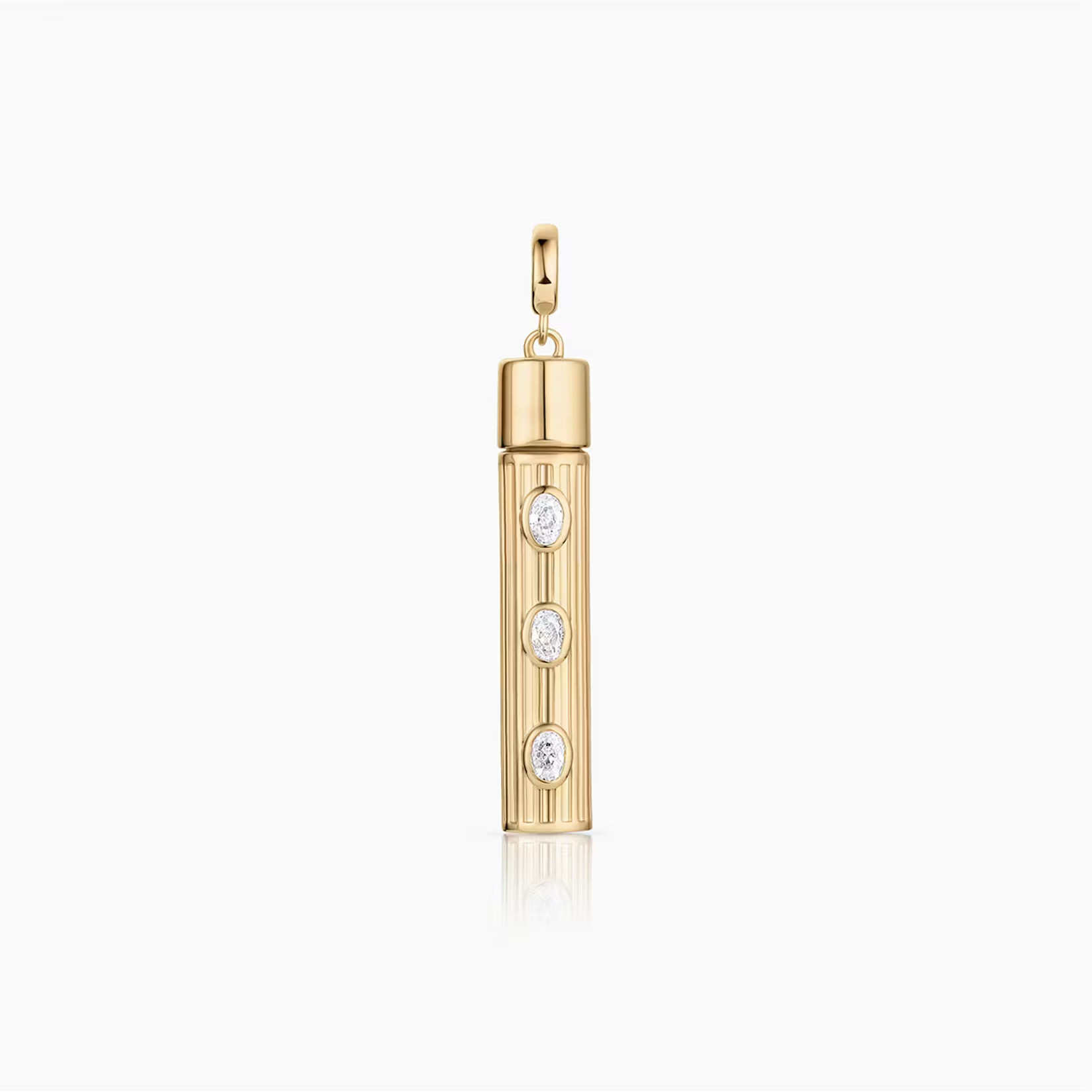 a tube shaped gold charm with three inlay white stones