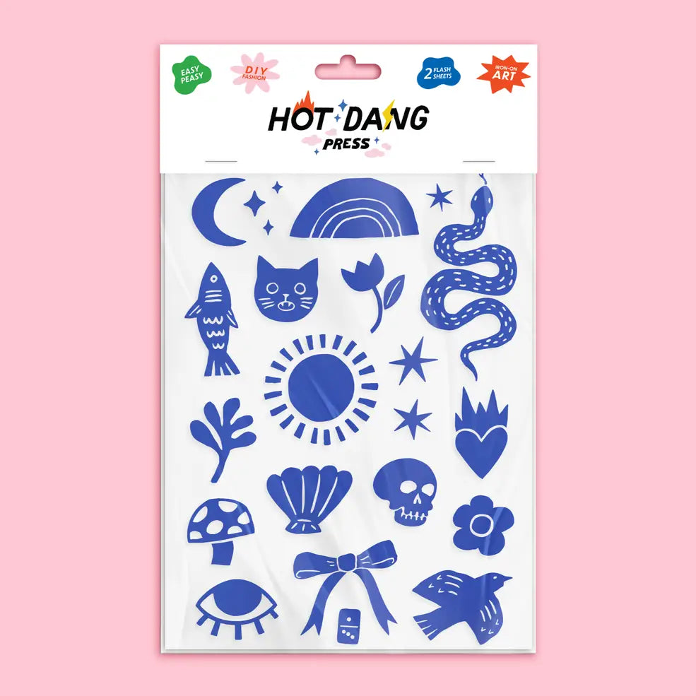 A sheet of blue and white hot stamp stickers from Hot D'ang Press, featuring whimsical doodle-style illustrations like a cat, rainbow, snake, mushroom, and eye, packaged on a white backing card against a solid pink background.