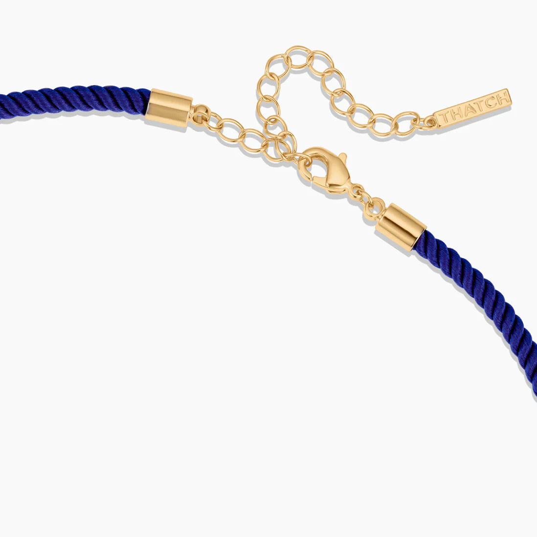 Blue cord bracelet with gold clasp and tag on a white background