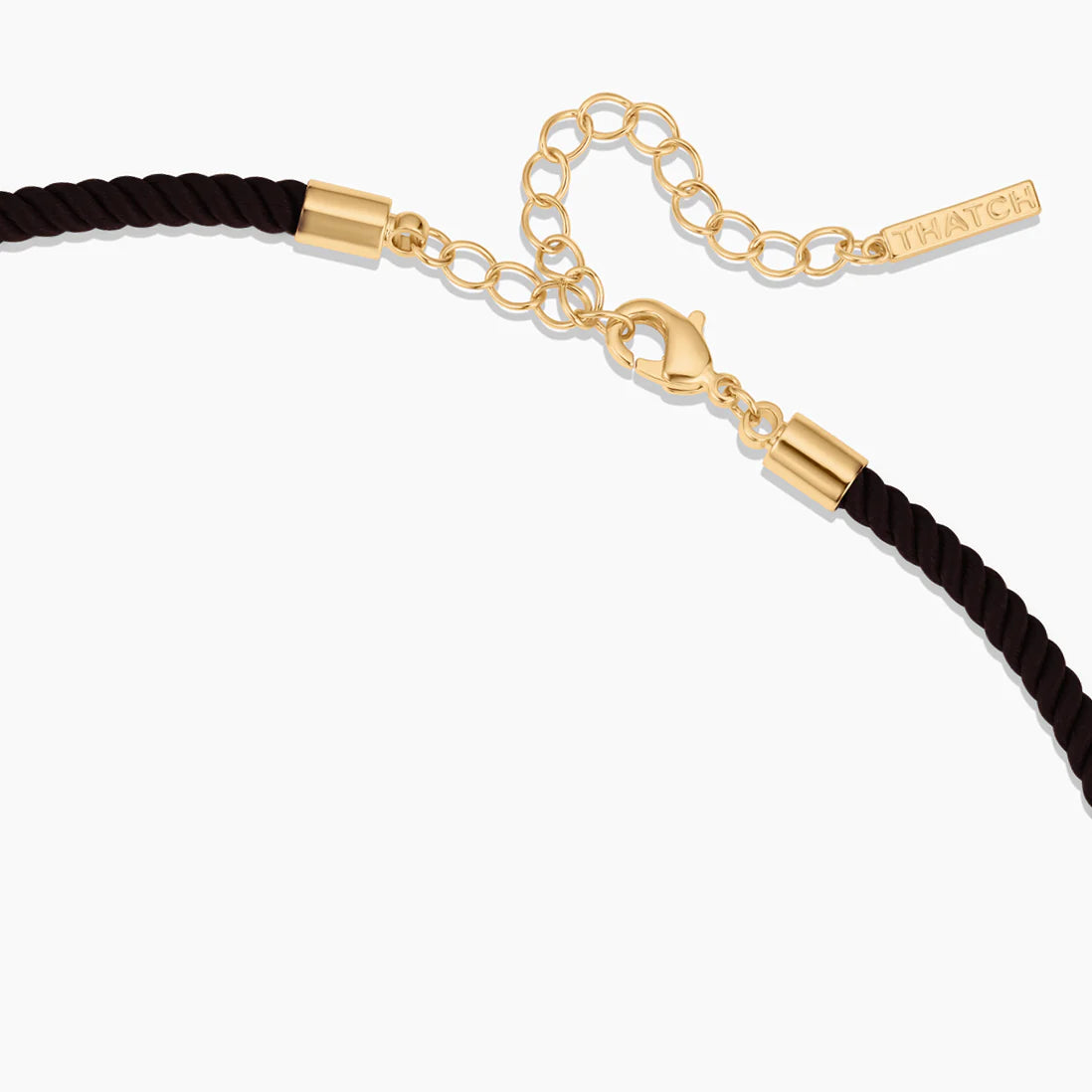 Black cord bracelet with gold clasp and tag on a white background