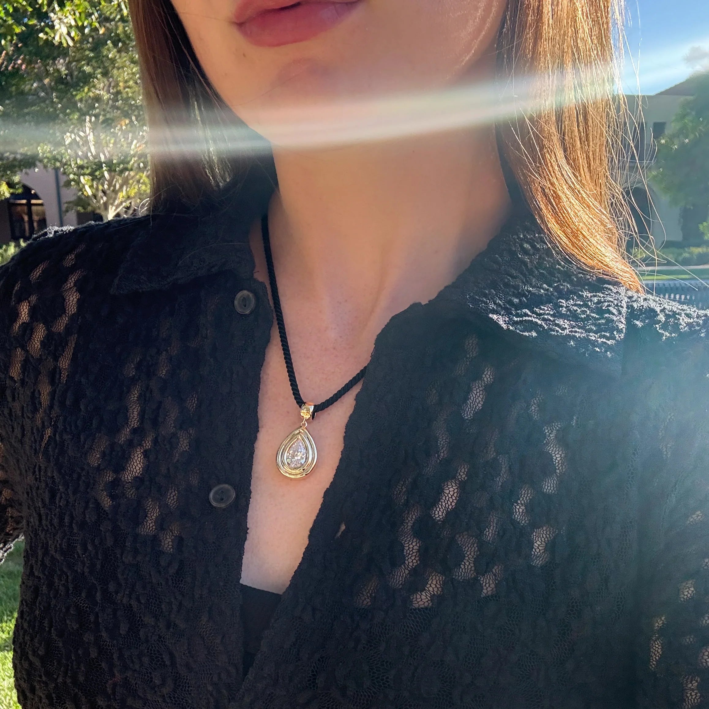 Person wearing a black lace top with a necklace outdoors