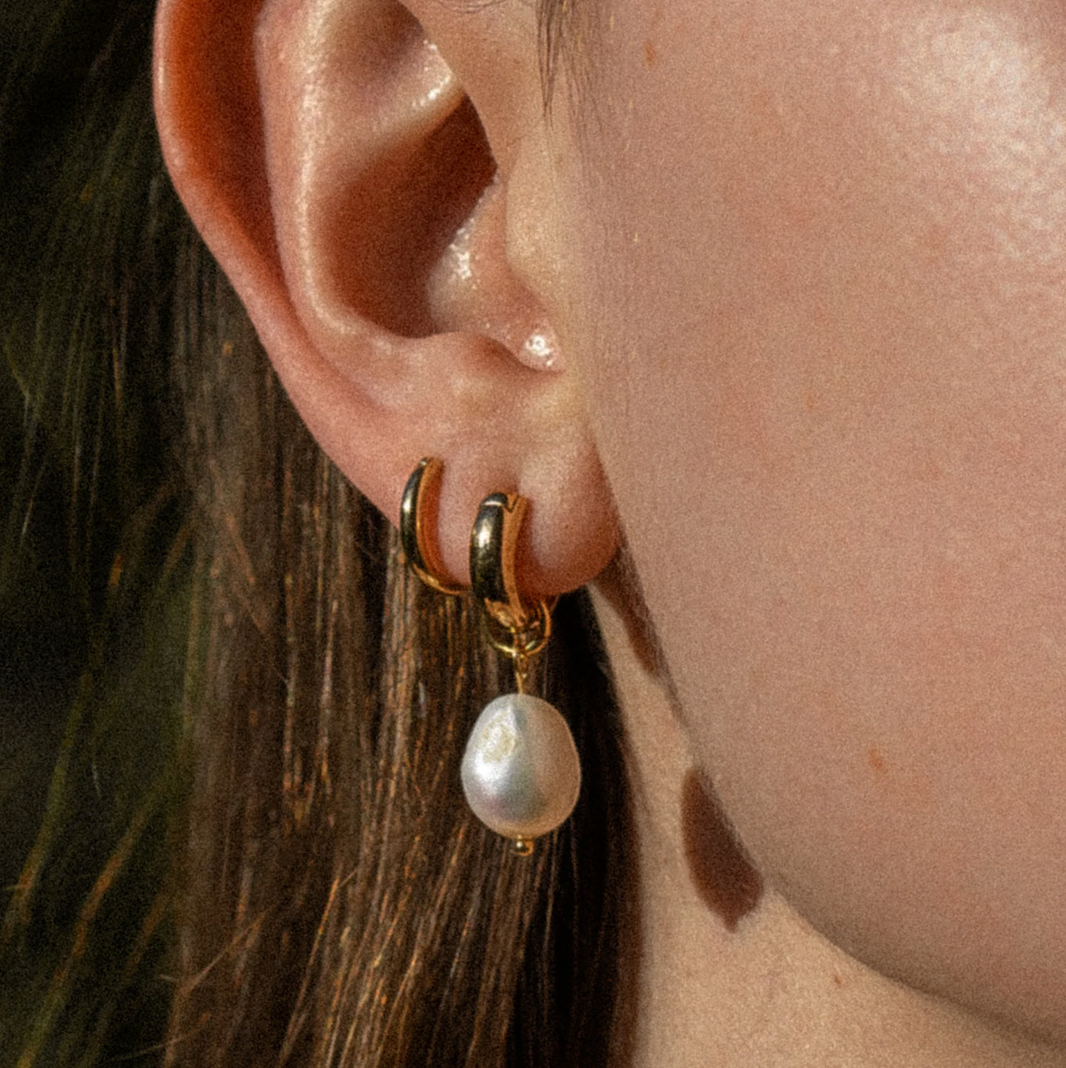 Colette Petite Pearl Earrings featuring gold-plated hoops and freshwater pearl charms, worn by a model, showcasing a stylish and elegant design.
