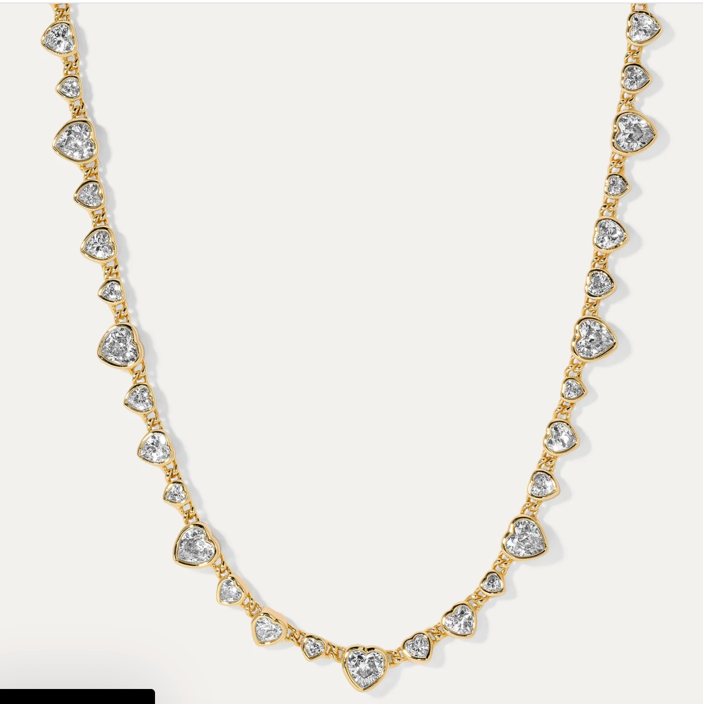 Gold necklace with heart-shaped diamond pendants on a white background