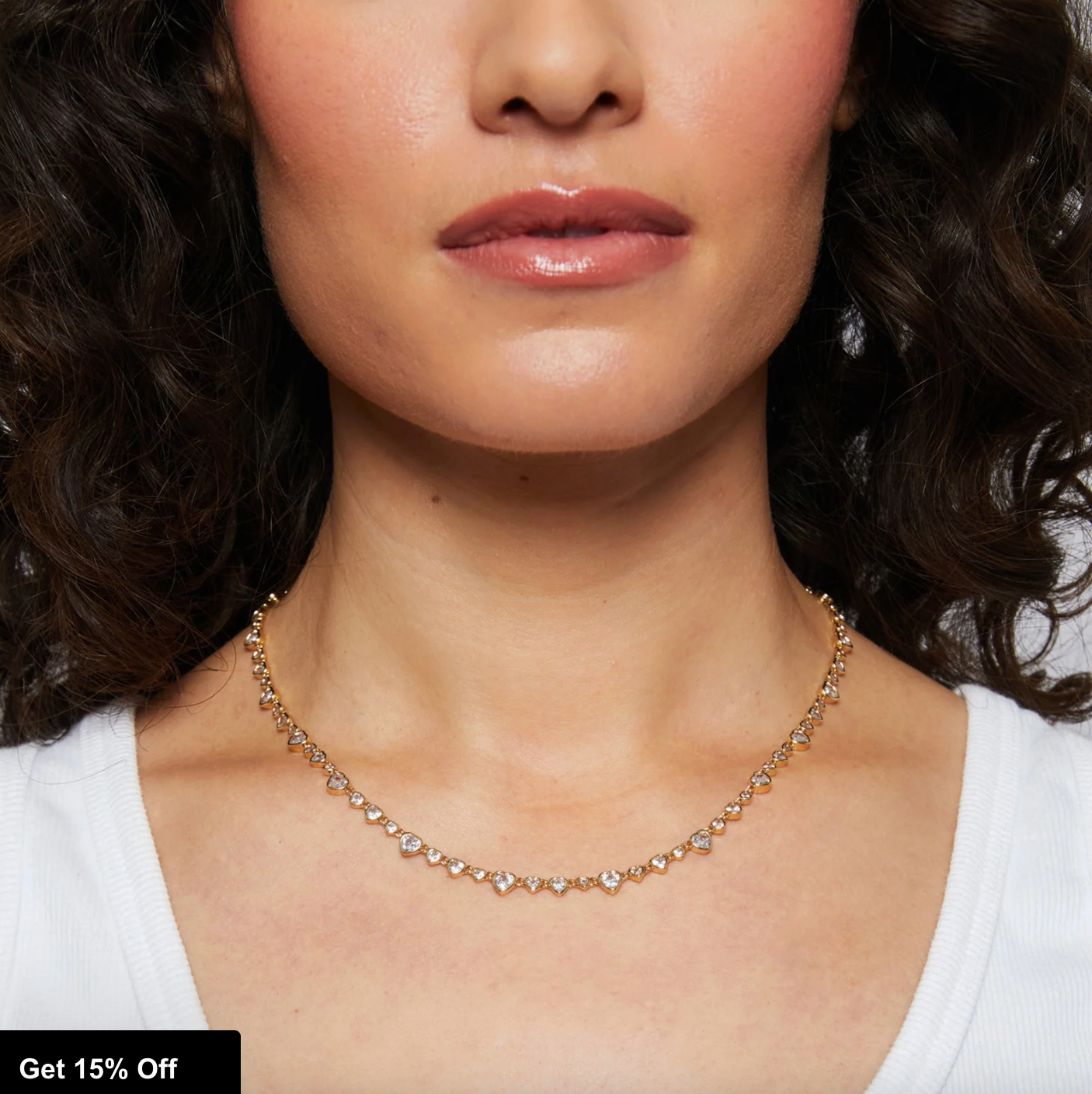 Close-up of a woman wearing a gold necklace with heart CZs with a blurred background