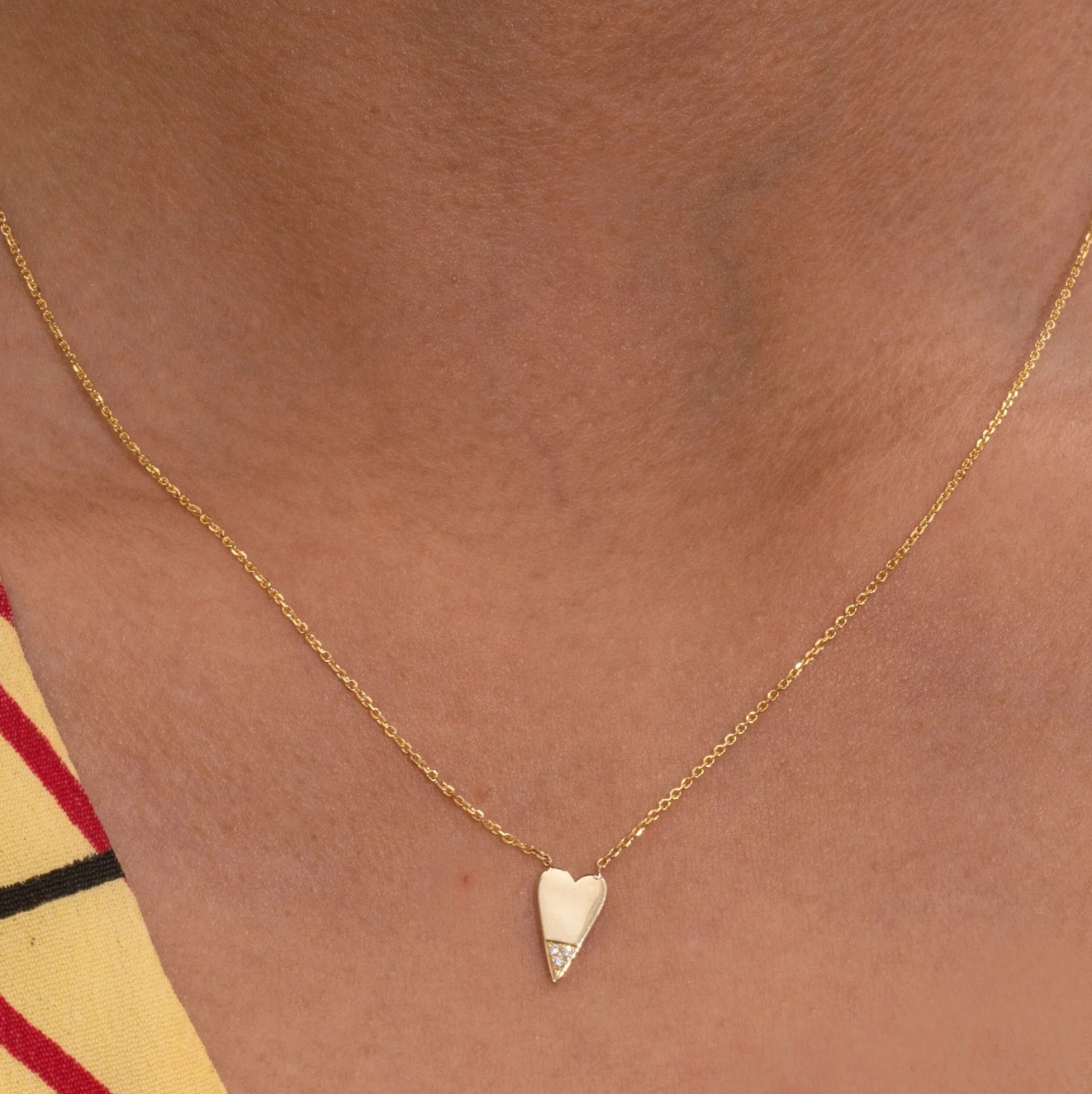  A slightly elongated heart dangles from a delicate cable chain, and the three small diamonds at the point have a way of catching light as you move. 