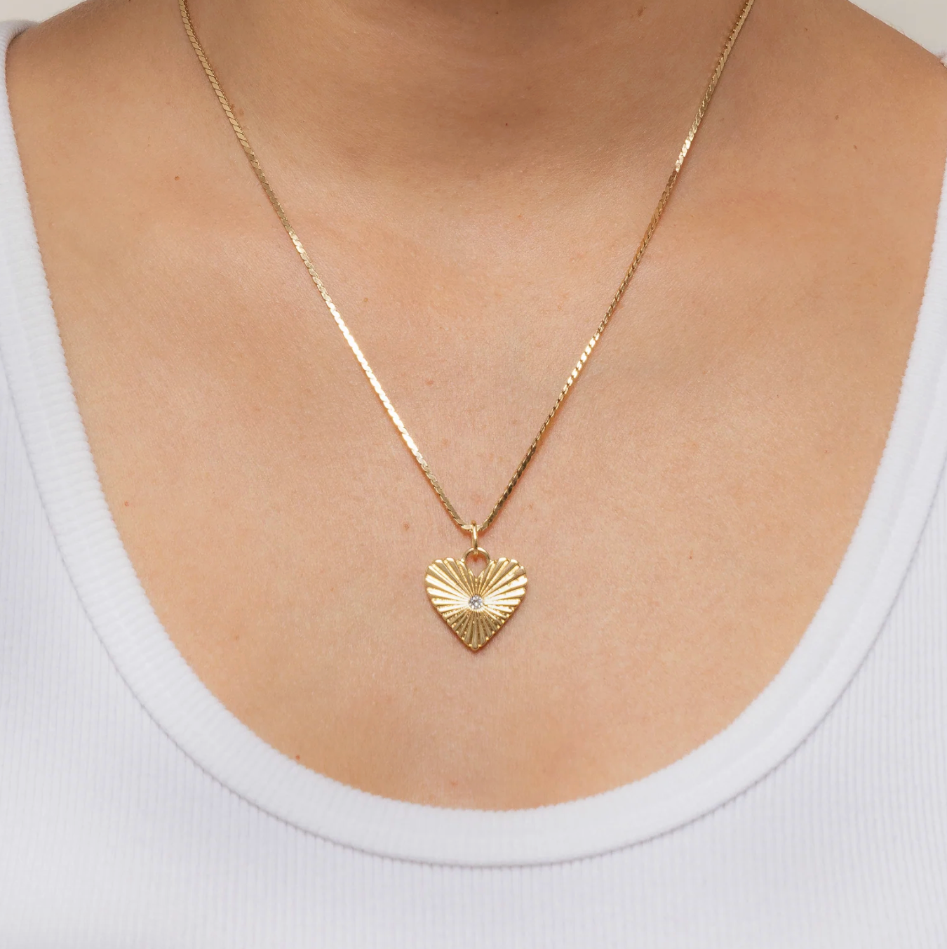 Gold Fluted heart-shaped necklace on a person wearing a white top
