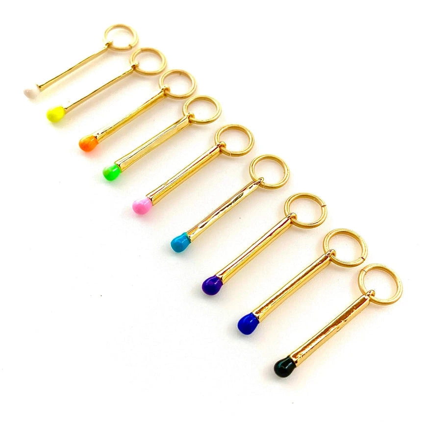 Gold match charms with rainbow colored tips on a white background