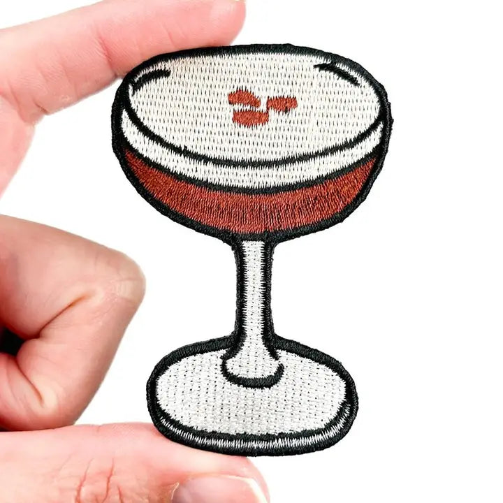 a brown black and white patch in the shape of an espresso martini on a white background