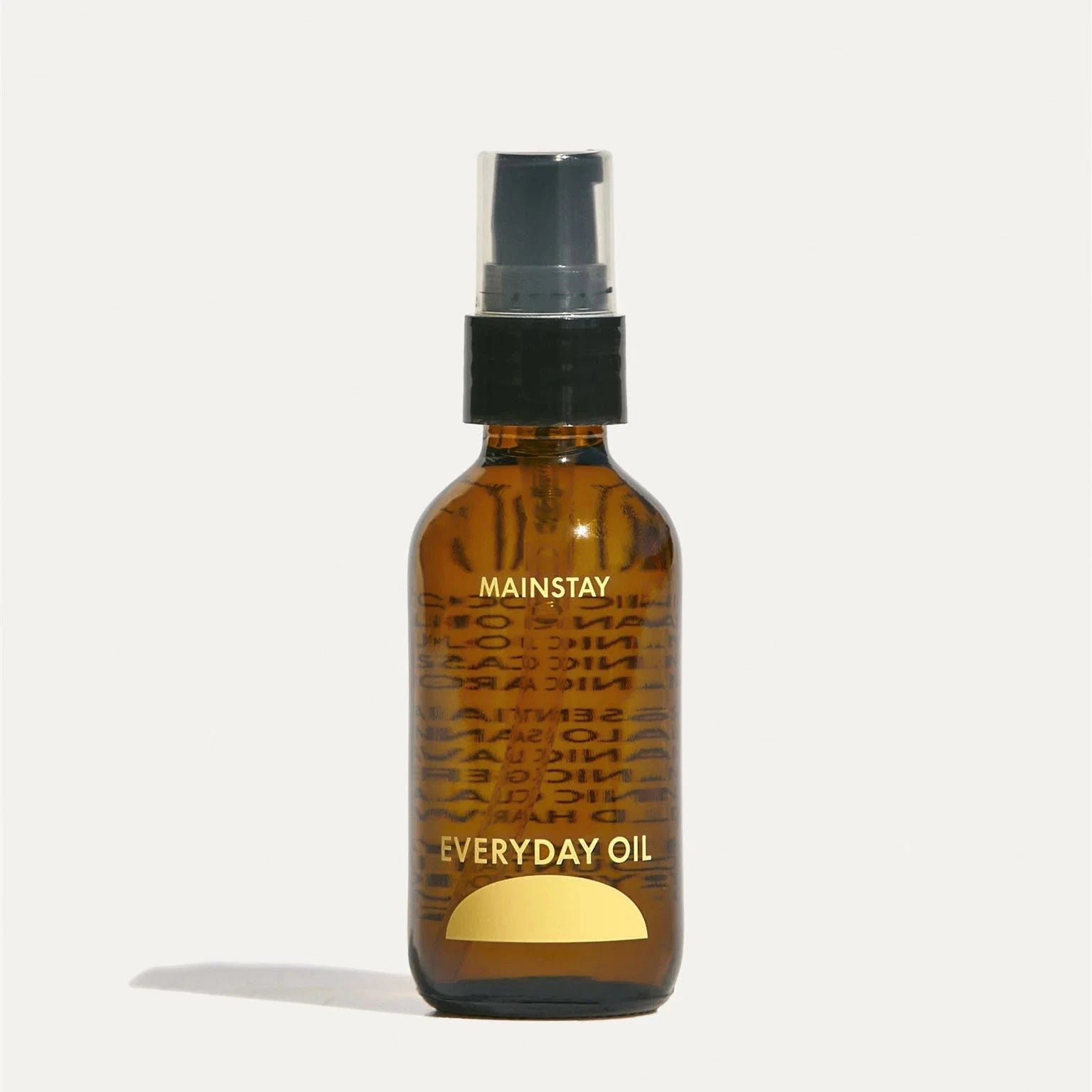 a small brown bottle filled with body oil with yellow text reading "mainstay" and "everyday oil" with a black spray top 