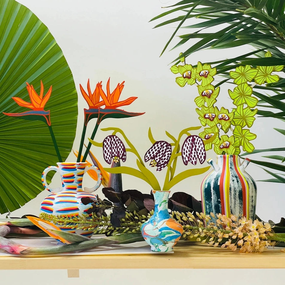 Colorful vases and floral arrangements on a table with a white background
