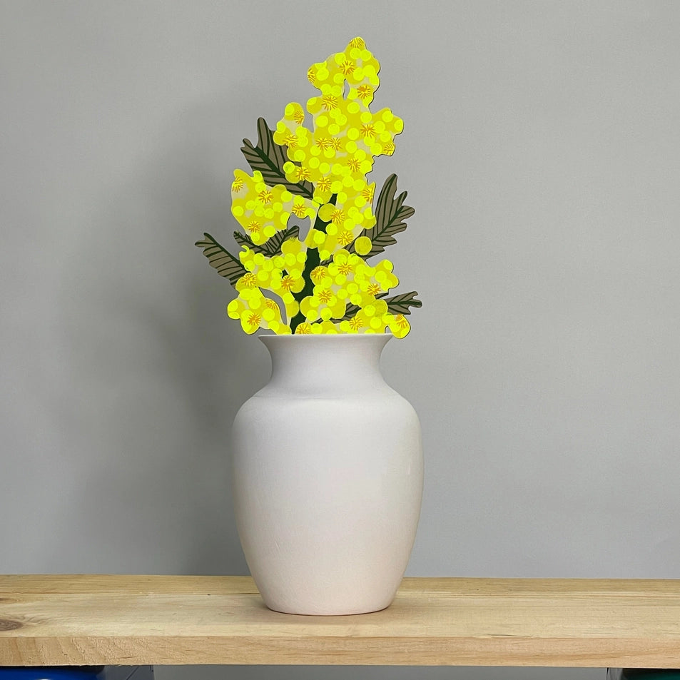 White vase with yellow flowers on a wooden surface against a gray background