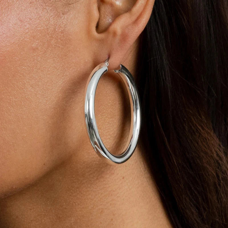 Close-up of a person wearing a silver hoop earring.
