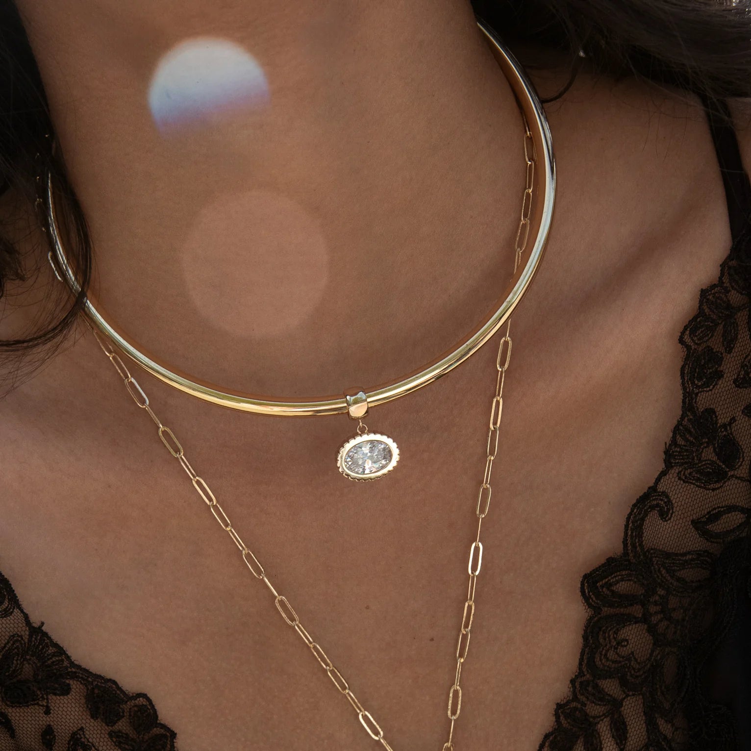 Gold necklaces on a person wearing a black lace garment.