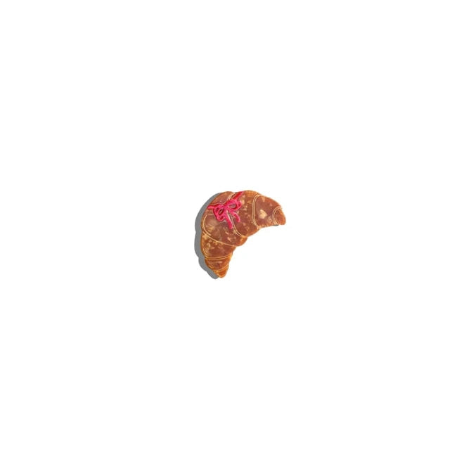 Top down view of croissant claw clip with pink bow on a white background