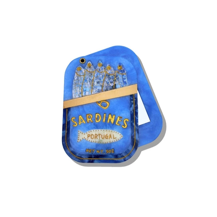 a blue compact mirror in the shape and with the design of a can of sardines on a white background