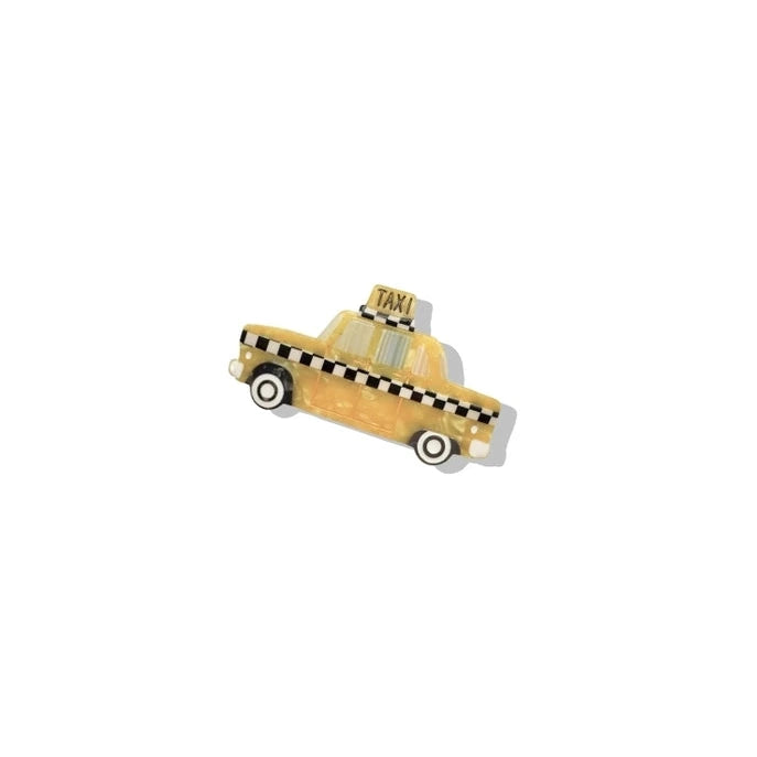 a yellow black and white painted brooch in the shape of a taxi on a white background