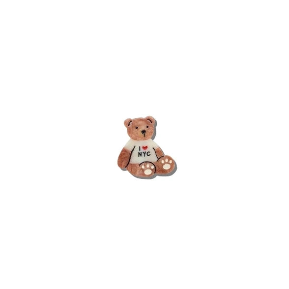 a brown and white painted brooch in the shape of a teddy bear wearing a shirt with text reading i love nyc on a white background