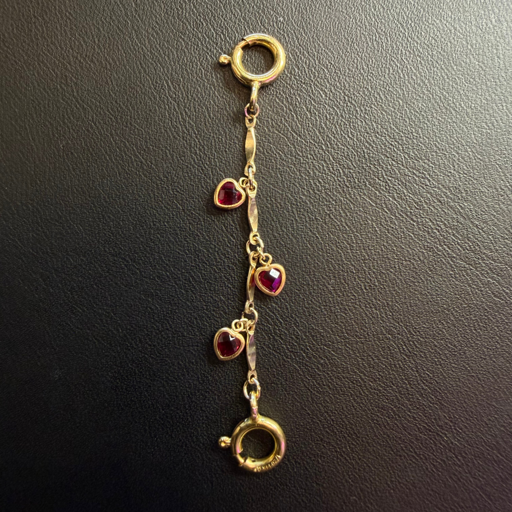 gold fill bar chain extender with three gold fill bezel set red cz hearts and two gold fill jumbo clasps on a black leather background