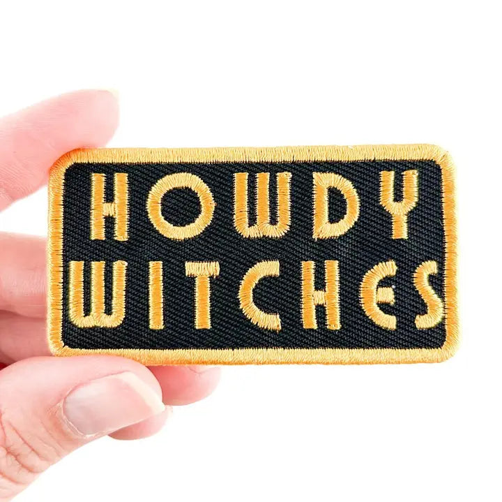 a black and yellow patch with text reading howdy witches on a white background