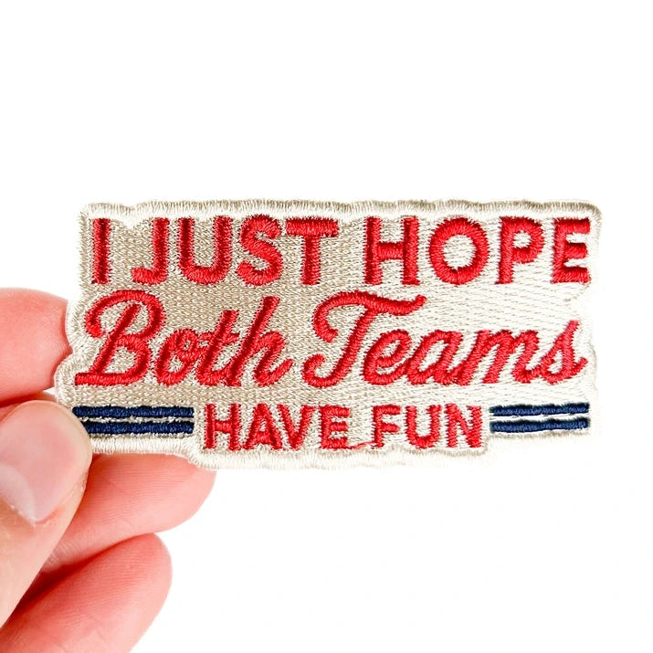 a red and white patch with text reading i just hope both teams have fun held by a hand over a white background