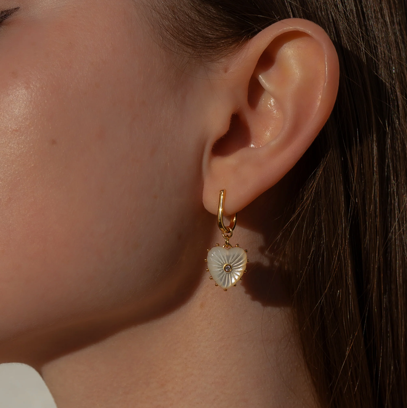14k gold plated hoop earrings with removable hand-carved mother of pearl heart charms and cubic zirconia center stones.