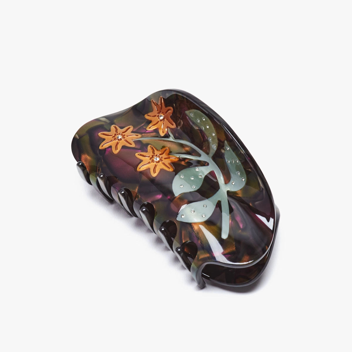 A black, purple, and green claw clip with a green and orange floral pattern on a white background