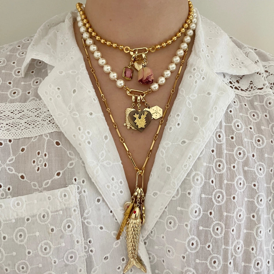 Gold necklace with heart pendant and tassel on a white blouse