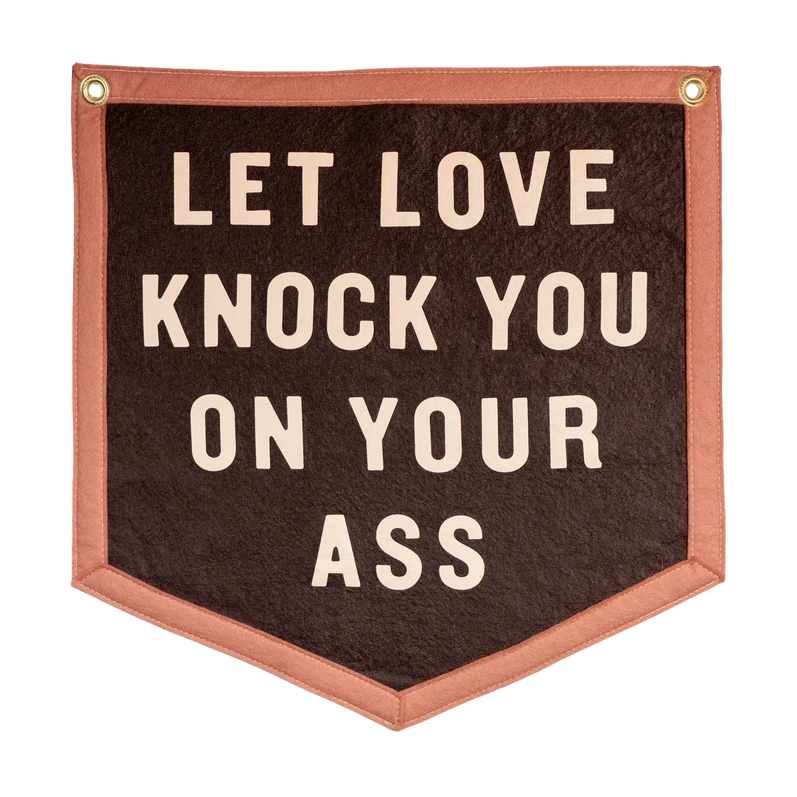a two toned brown camp flag that reads let love knock you on your ass over a white background