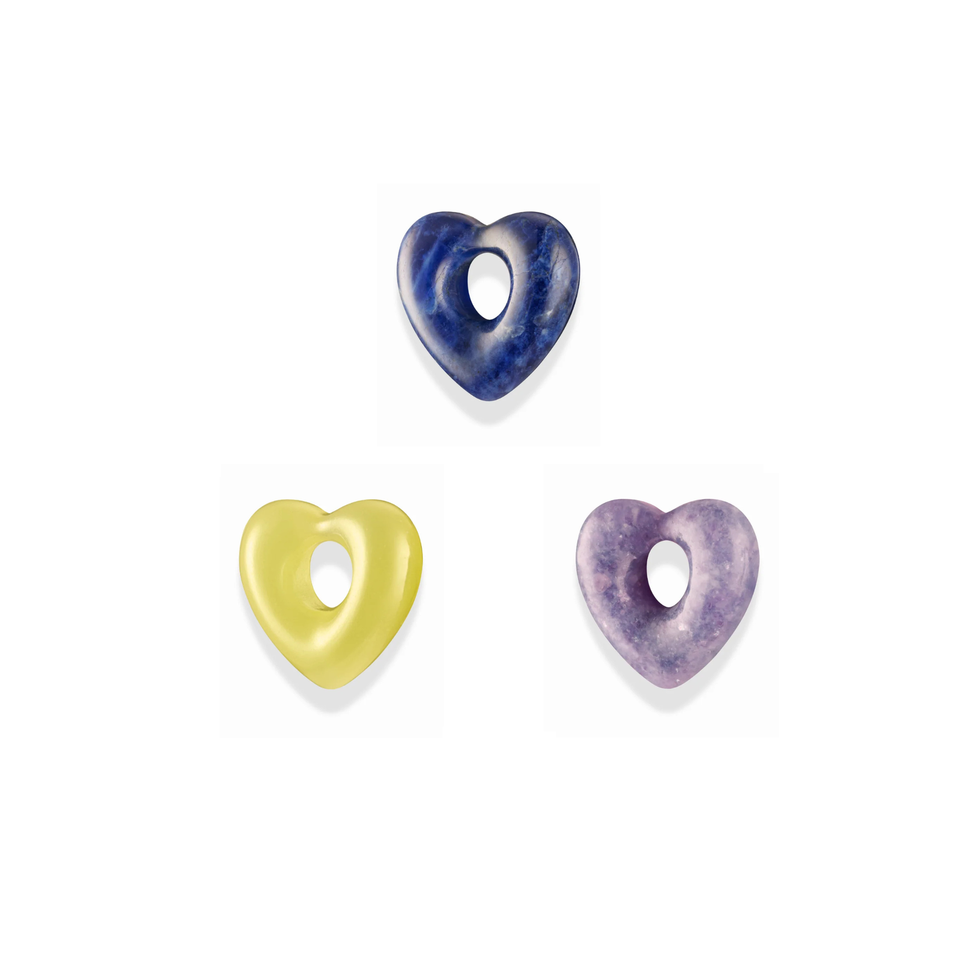 three different colored heart shaped gemstone shaper charms over a white background