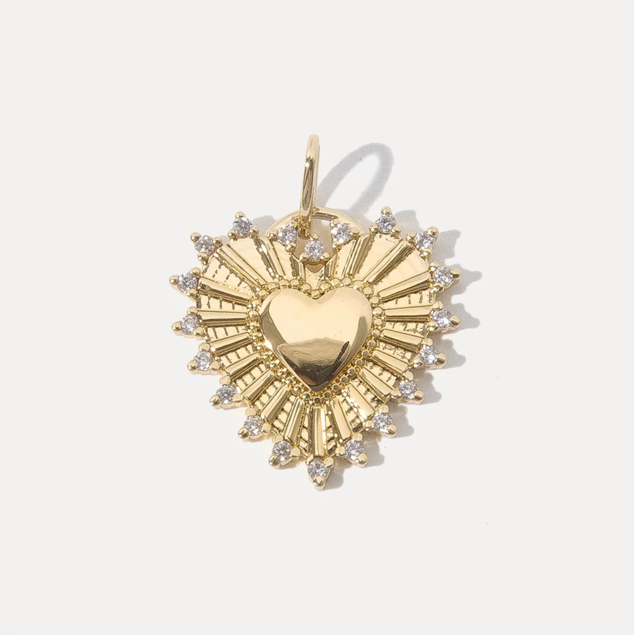 Gold heart pendant with sunburst design on a white background