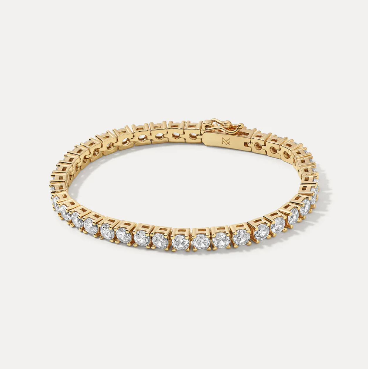 Gold tennis bracelet with CZs on a light gray background