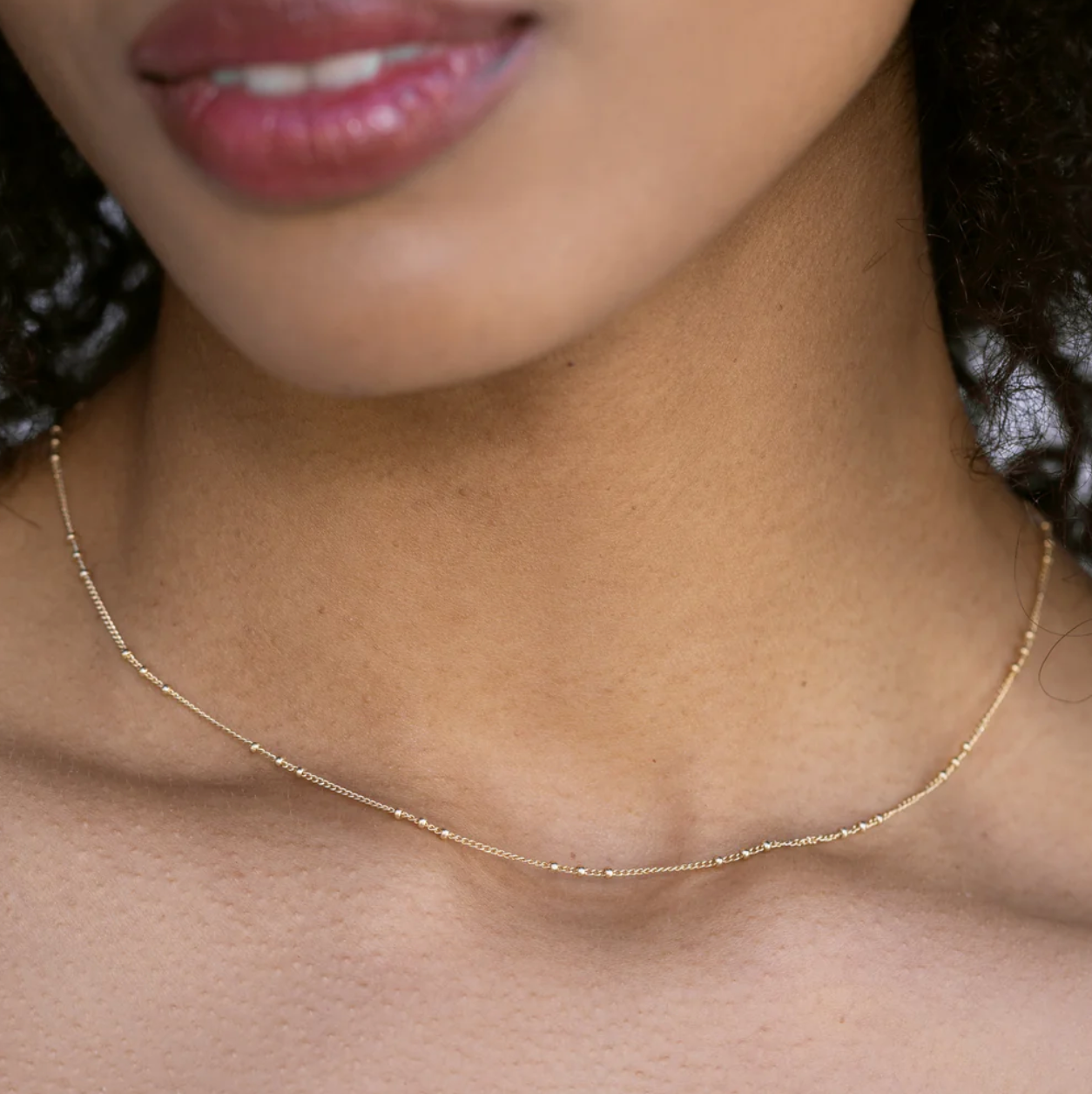 Close-up of a person wearing a delicate gold necklace.